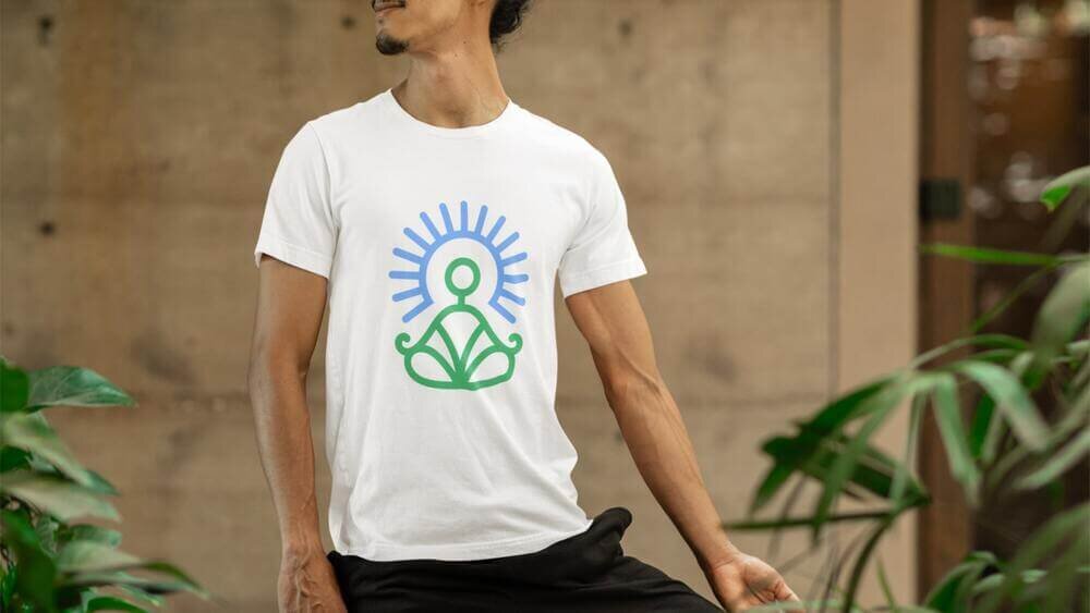 A man wearing a custom white Gilda 64000 t-shirt with a line illustration of a person doing yoga.