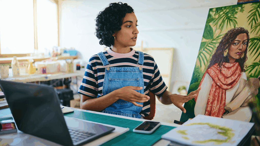 A woman presenting her art using a laptop to earn passive income as an artist.