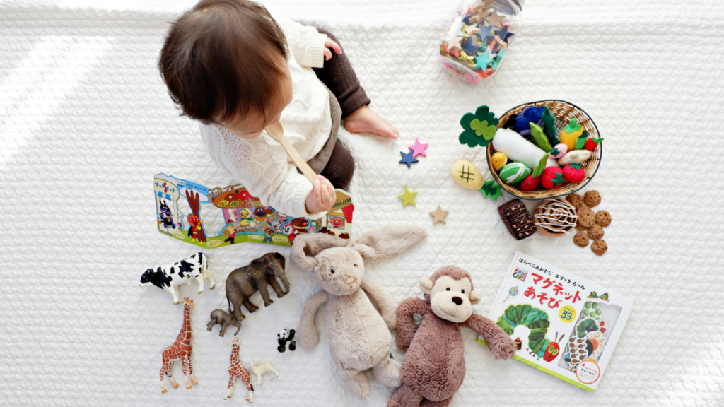 A child playing with various toys on a white blanket.