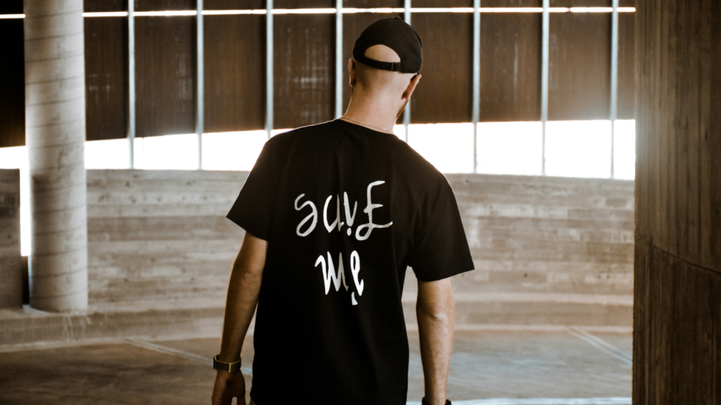 A man in a black shirt with a white “Save me” print on the back.