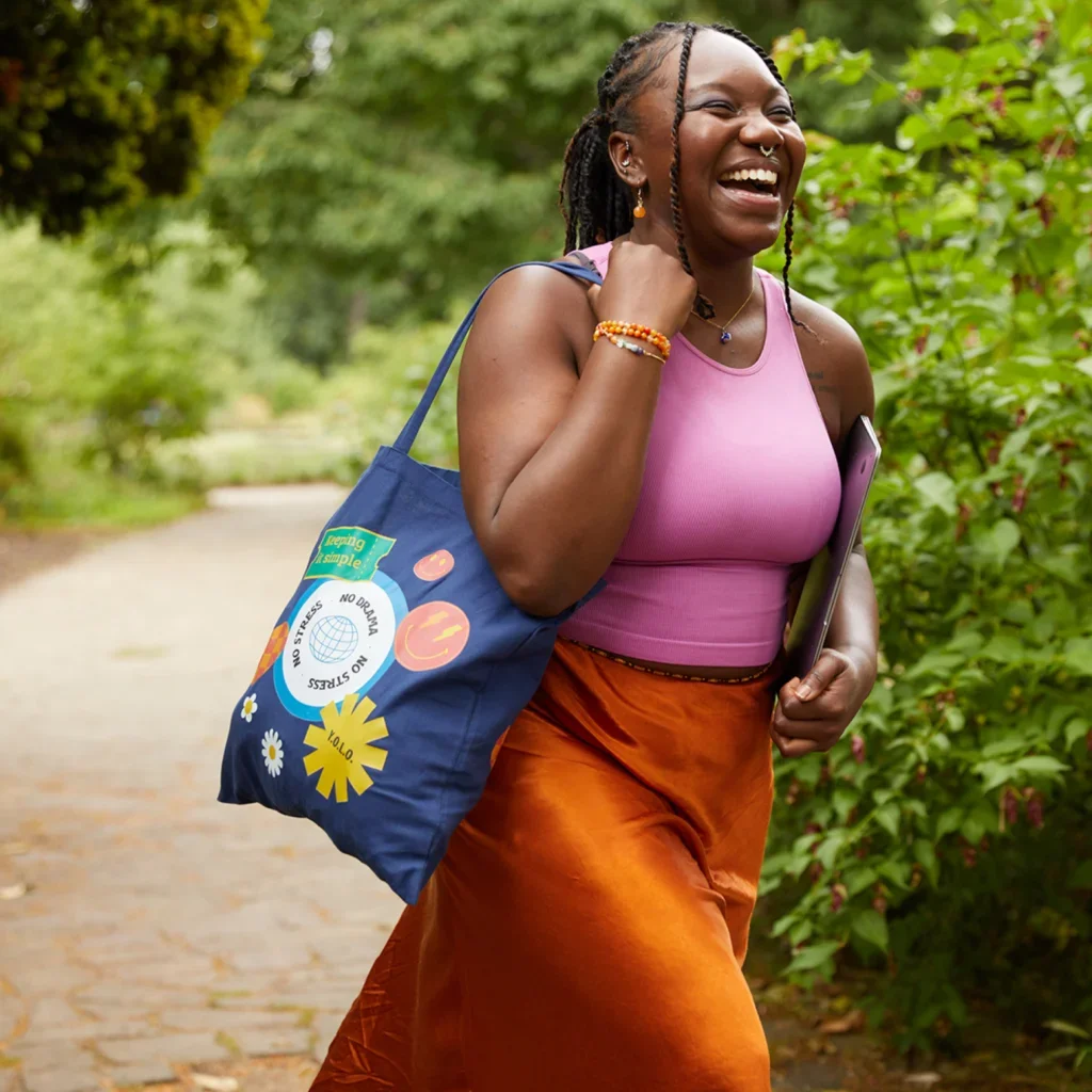 A woman, smiling and wearing a custom-printed tote bag, showcasing ideas on how to make $2000 a month with print-on-demand.
