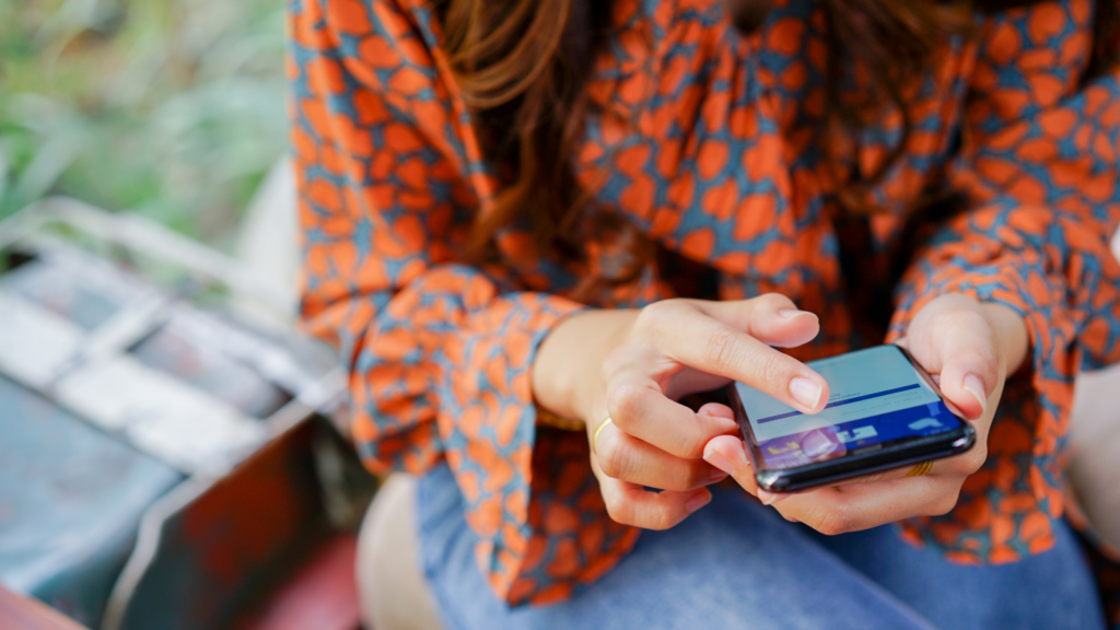 A woman with a phone in her hand preparing a listing to sell on Facebook Marketplace.