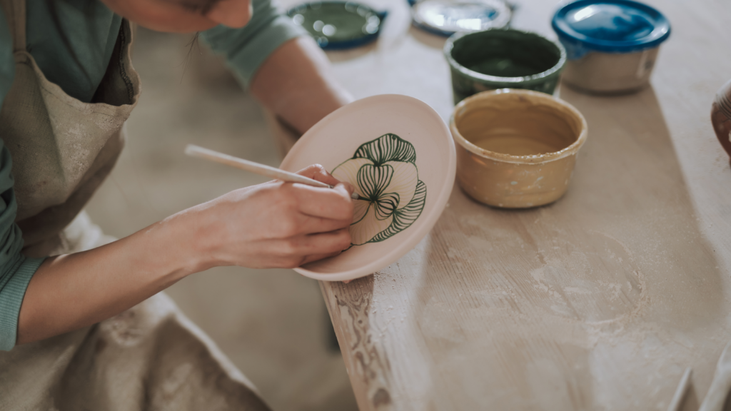 A woman coloring a handmade dish.