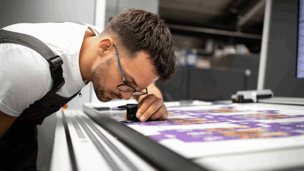 A man in glasses is inspecting a print.