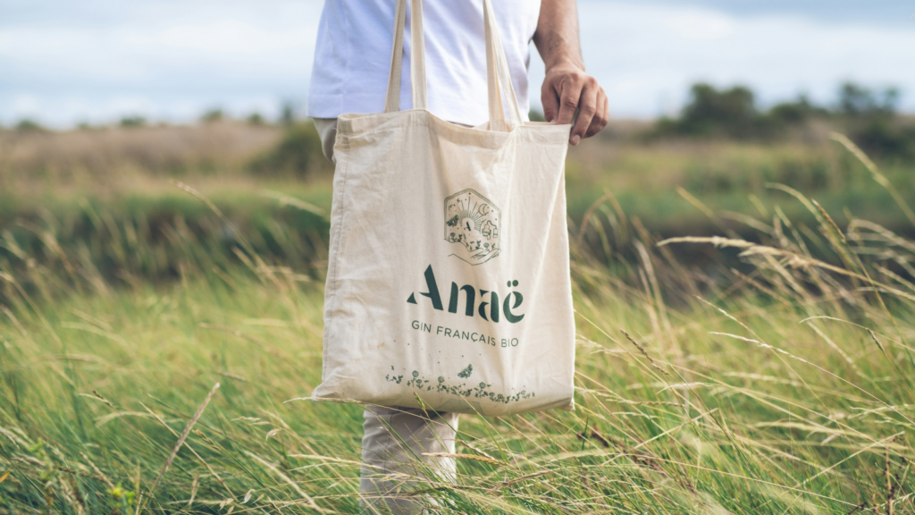 A man carries a tote bag while walking in a field.