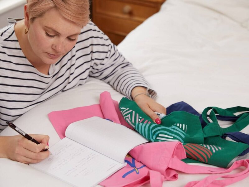 A woman checking the quality of custom tote bag samples.