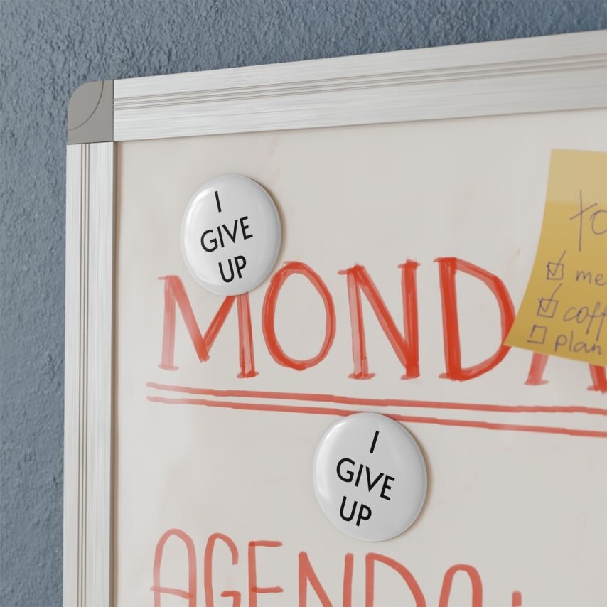 Round magnets with the words “I give up” printed on them.
