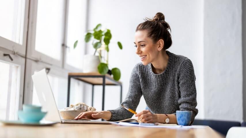 A woman looking at a laptop screen and smiling.