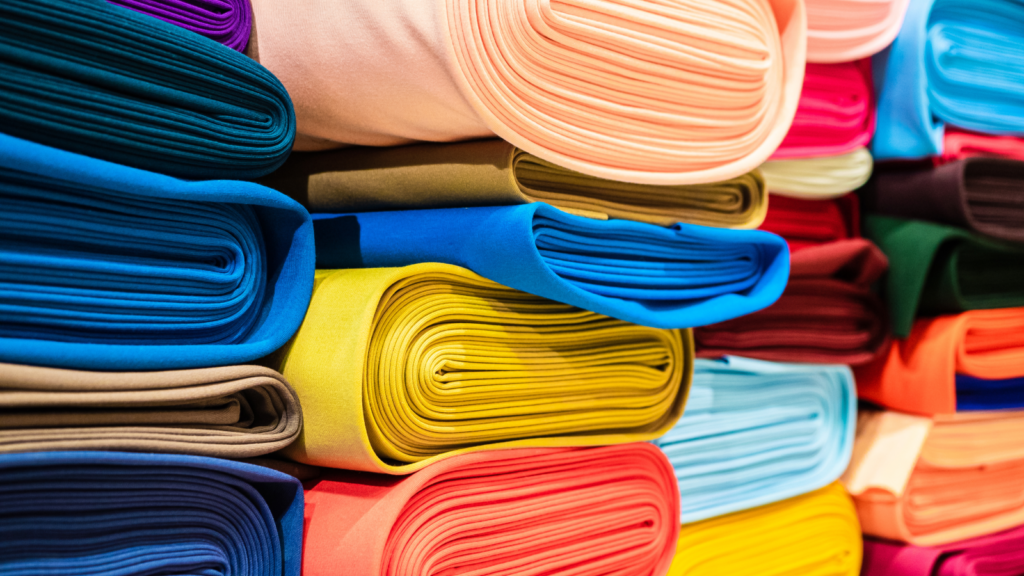 A stack of cotton fabric rolls in various colors.