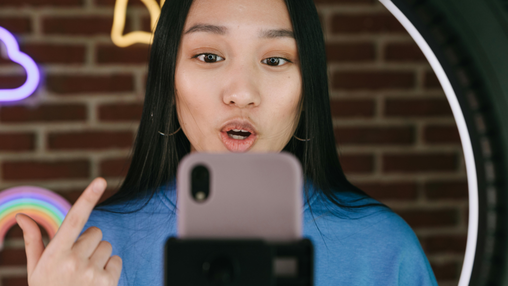 A woman looking directly at a mobile phone while filming herself.