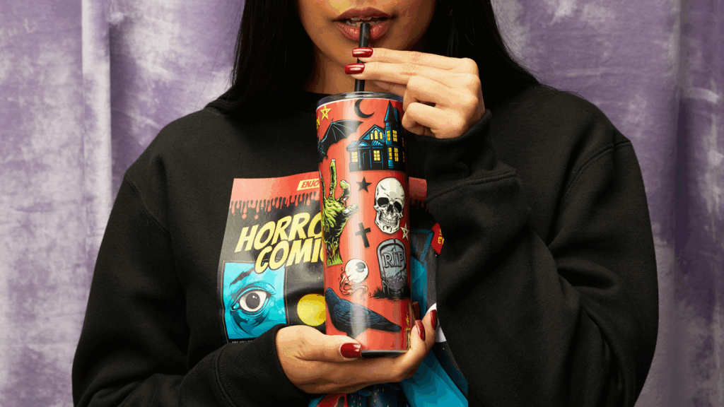 A woman with dark hair in a black sweatshirt holds a cup, smiling softly at the camera.