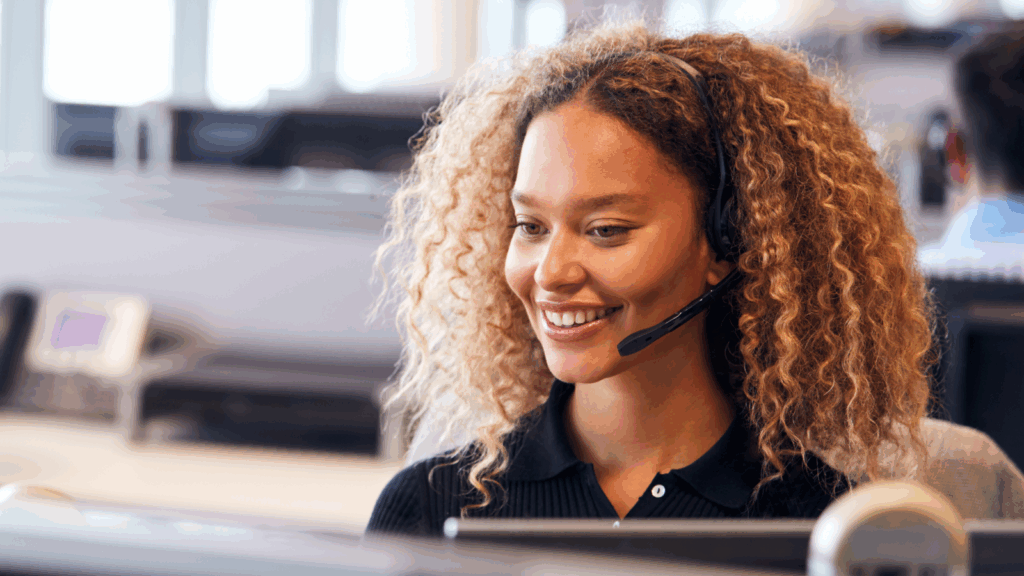 A woman wearing a headset, focused on her work in a modern office environment.