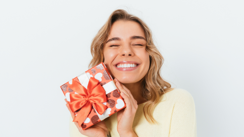 A woman joyfully holds a beautifully wrapped women’s day gift.