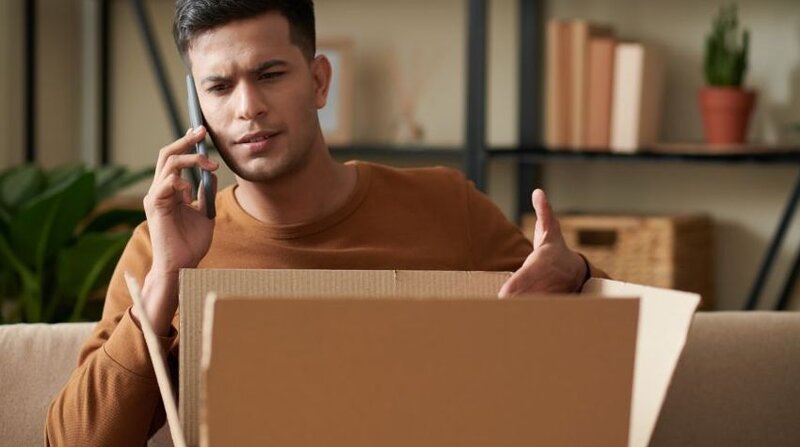 Man speaking on the phone about a delivered package he is not happy with.