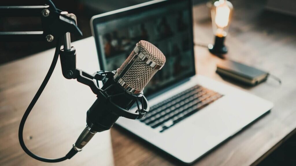 A laptop and a microphone set up for recording a podcast.