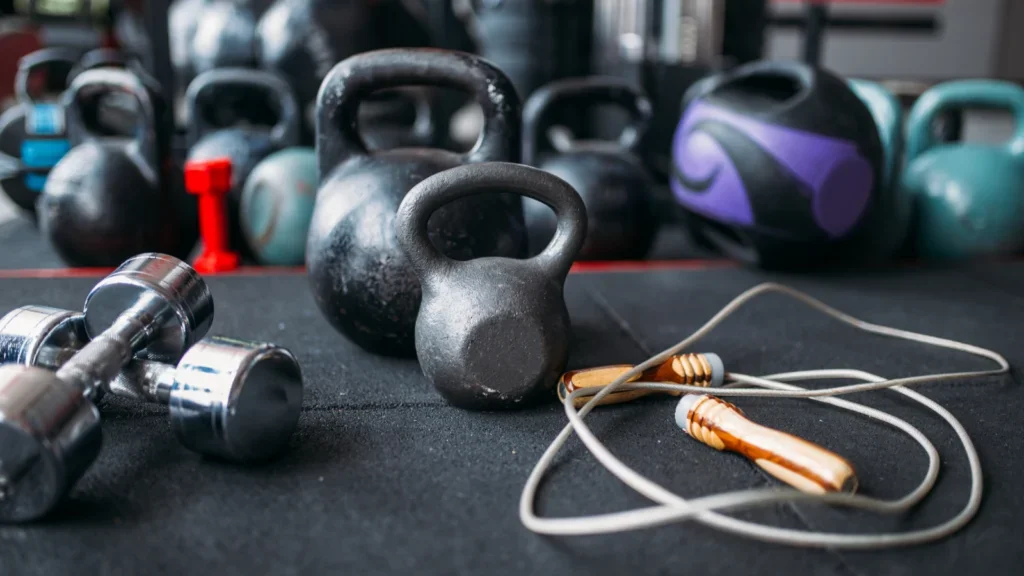 A selection of kettlebells and dumbbells arranged on a black surface, showcasing various weights and sizes.