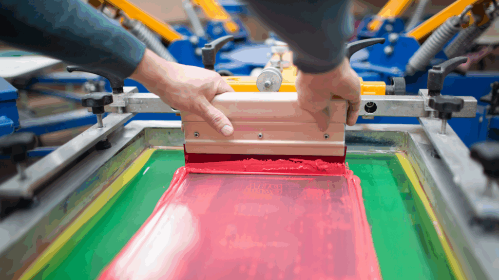 A person making customized apparel using screen printing.