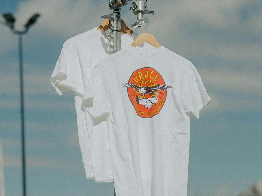 Two printed t-shirts hanging on a metal construction.