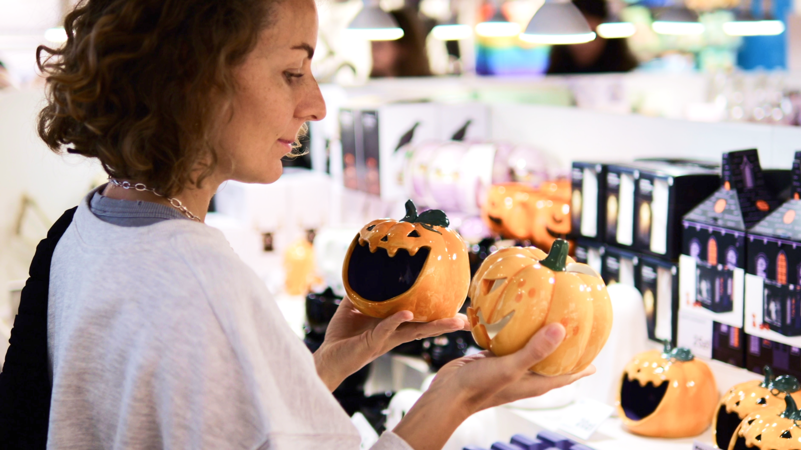 A woman is shopping for ceramic Halloween pumpkins.