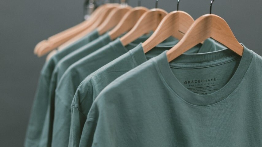 Green shirts hanging on the hangers on the tray.