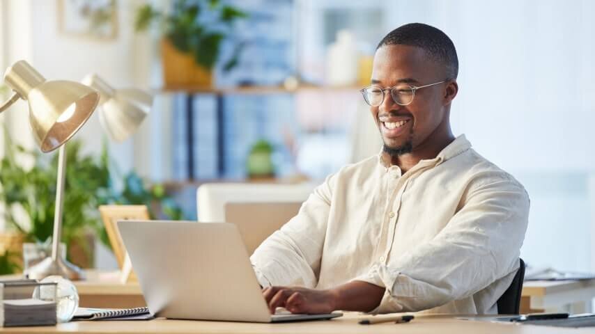 A smiling man working on his laptop.