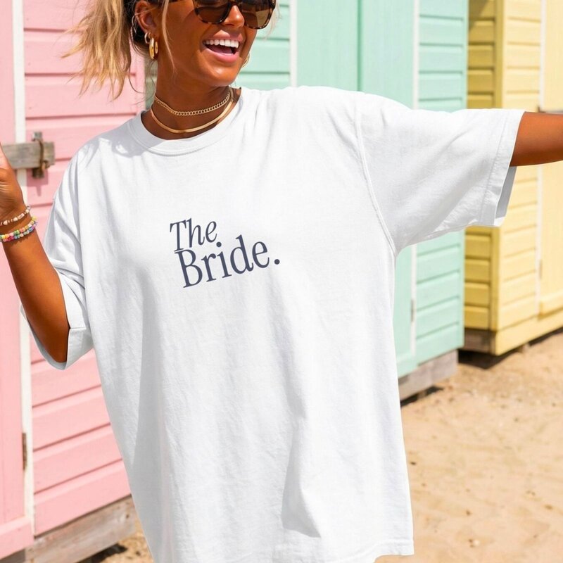 A white t-shirt with the text "Bride" in elegant script, adorned with floral designs, perfect for bridal celebrations.