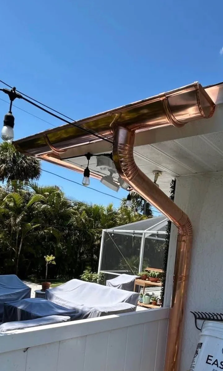 Copper seamless gutter and downspout installed beside a screened patio