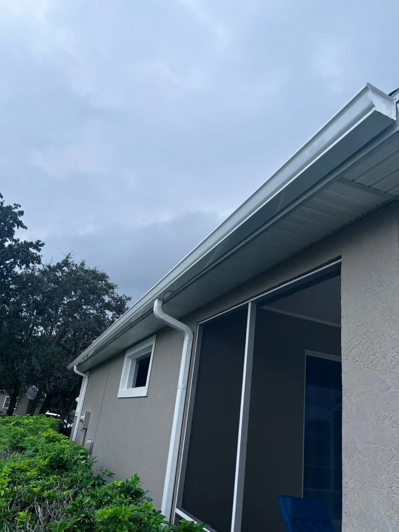 White gutter and downspout along a screened patio