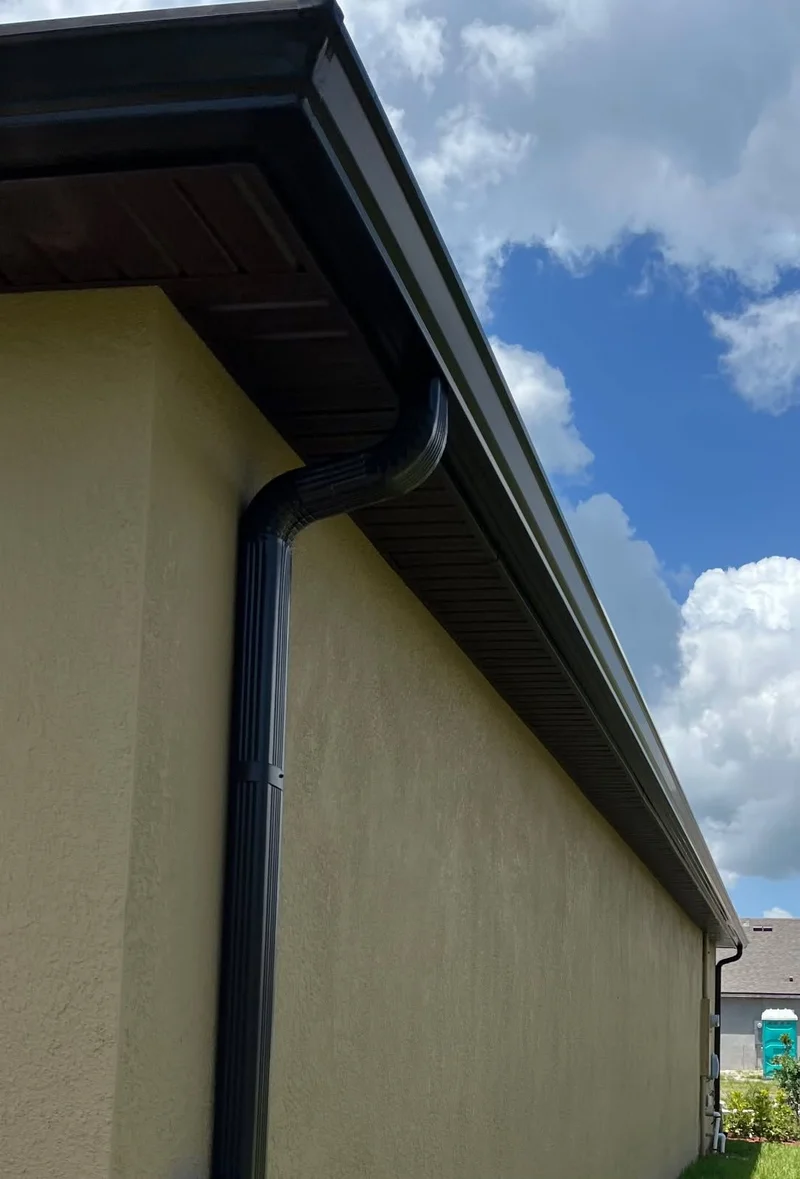 Close-up of a dark downspout and gutter corner