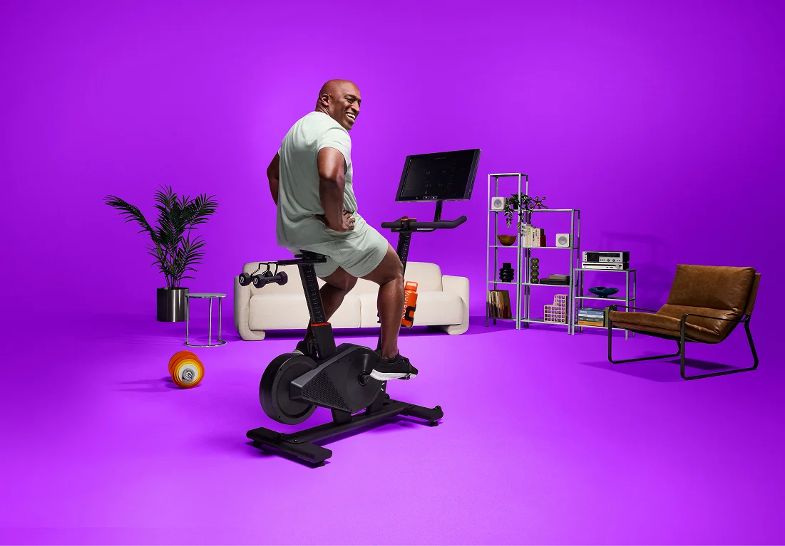 Man standing to climb during a stationary bike interval workout on the Aviron Fit Bike S