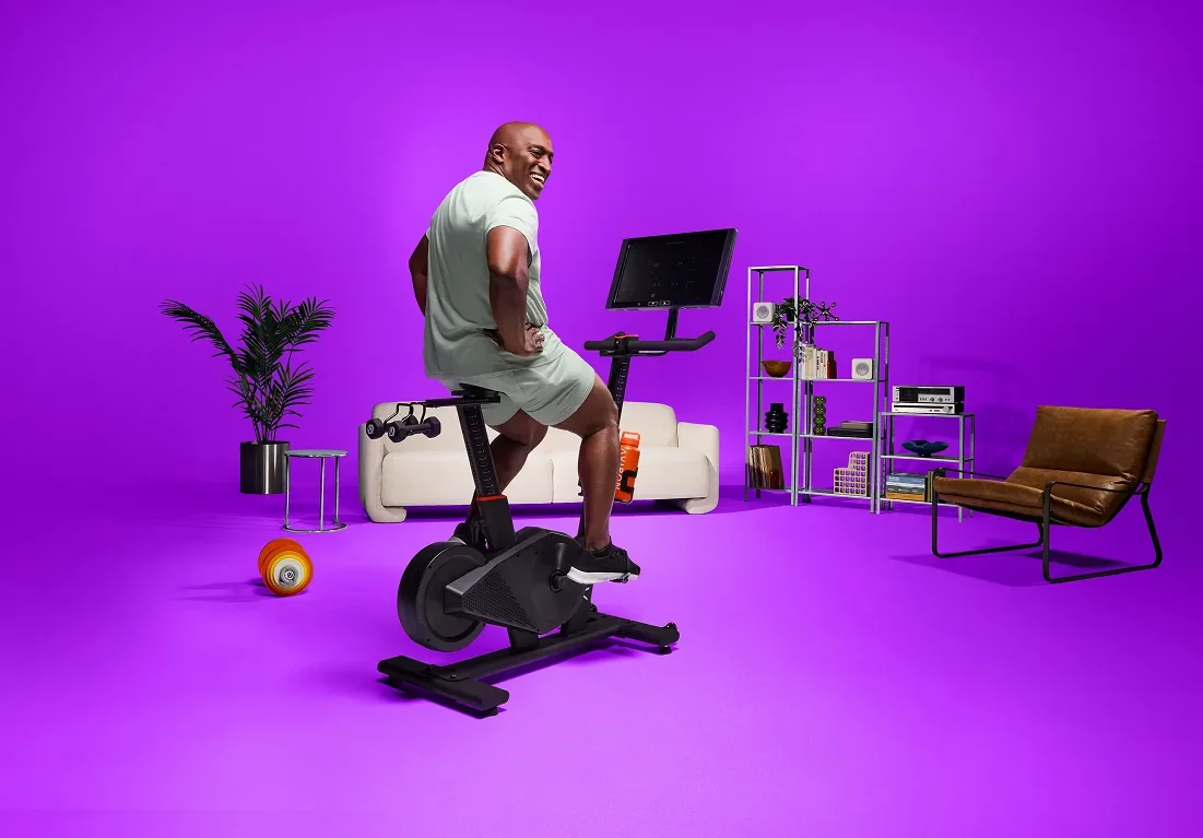 Man doing a stationary bike workout at home in front of a couch