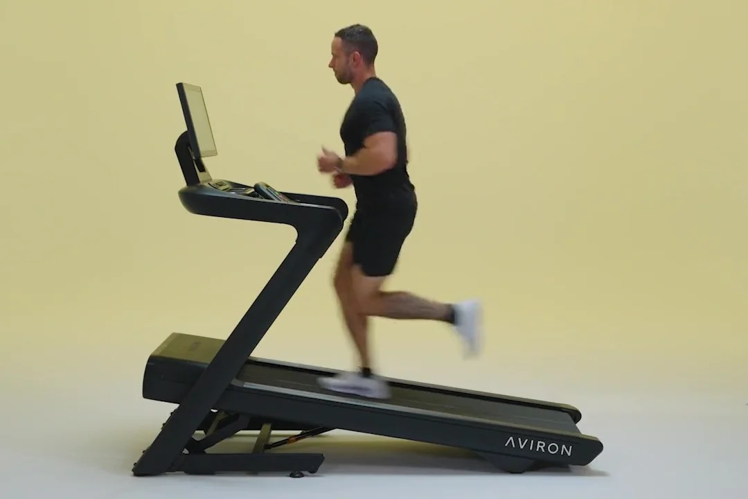 Man running on the Aviron Justice compact folding treadmill set to an incline
