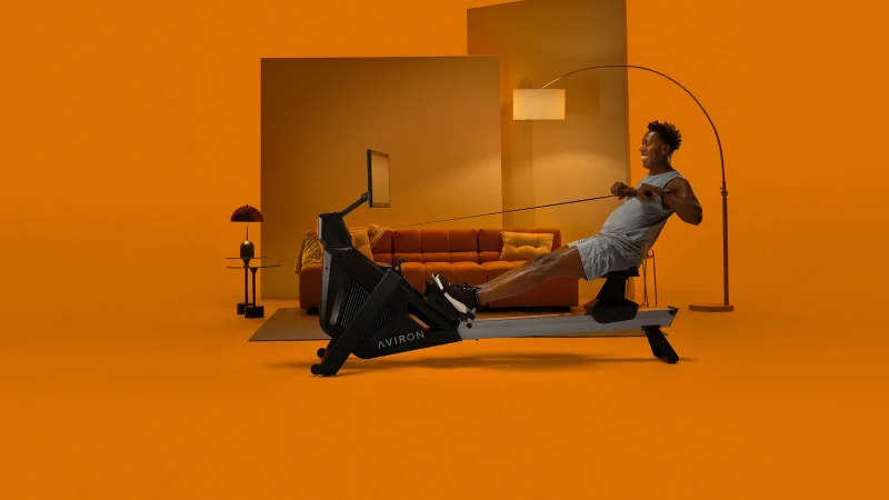 Rowing at full extension on an Aviron Strong Series Rower for full-body conditioning