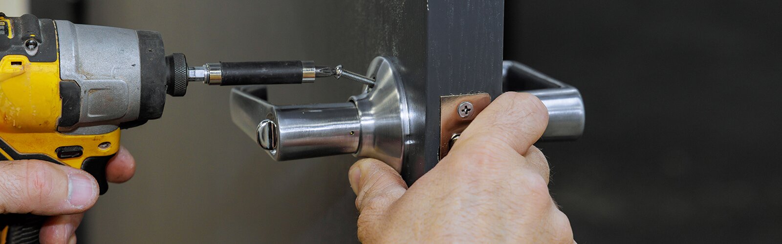 Using a screwdriver, carpenter installs lock handles on room door