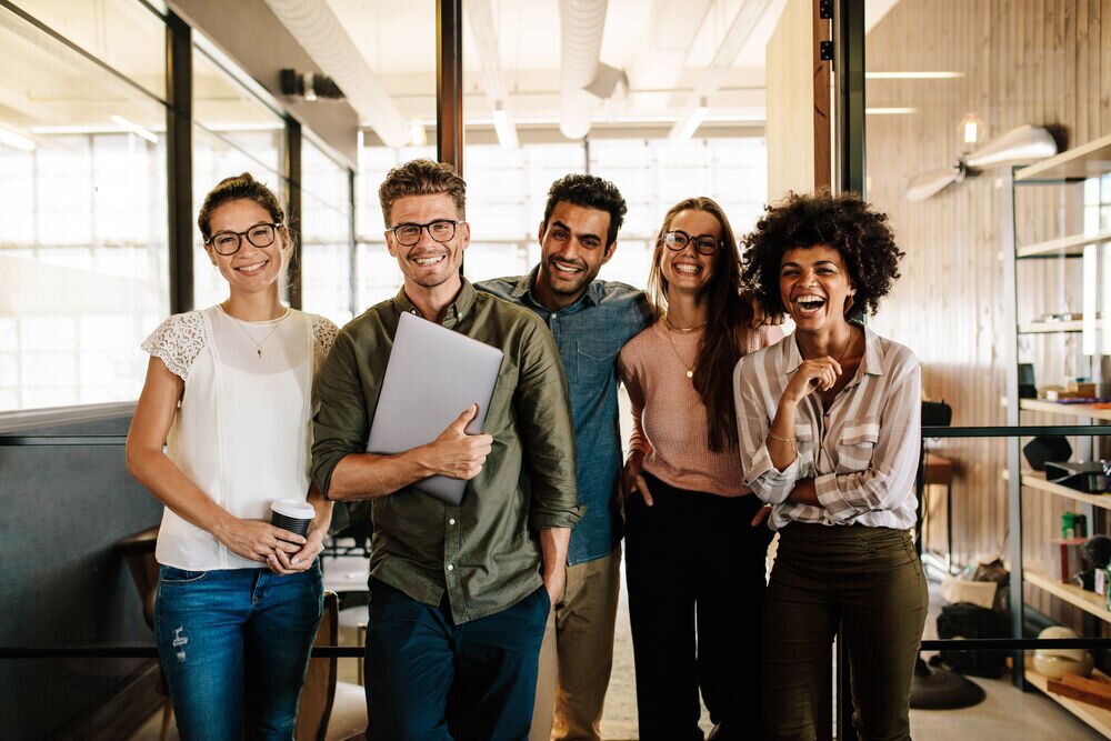 Group of coworkers smiling and interacting in a modern office setting