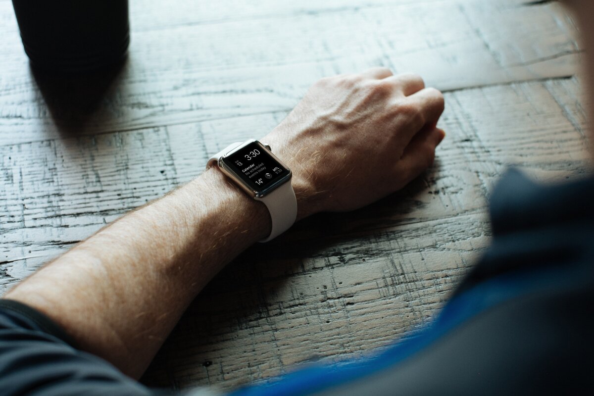 Man's arm resting on a table with a smartwatch showing 3:30