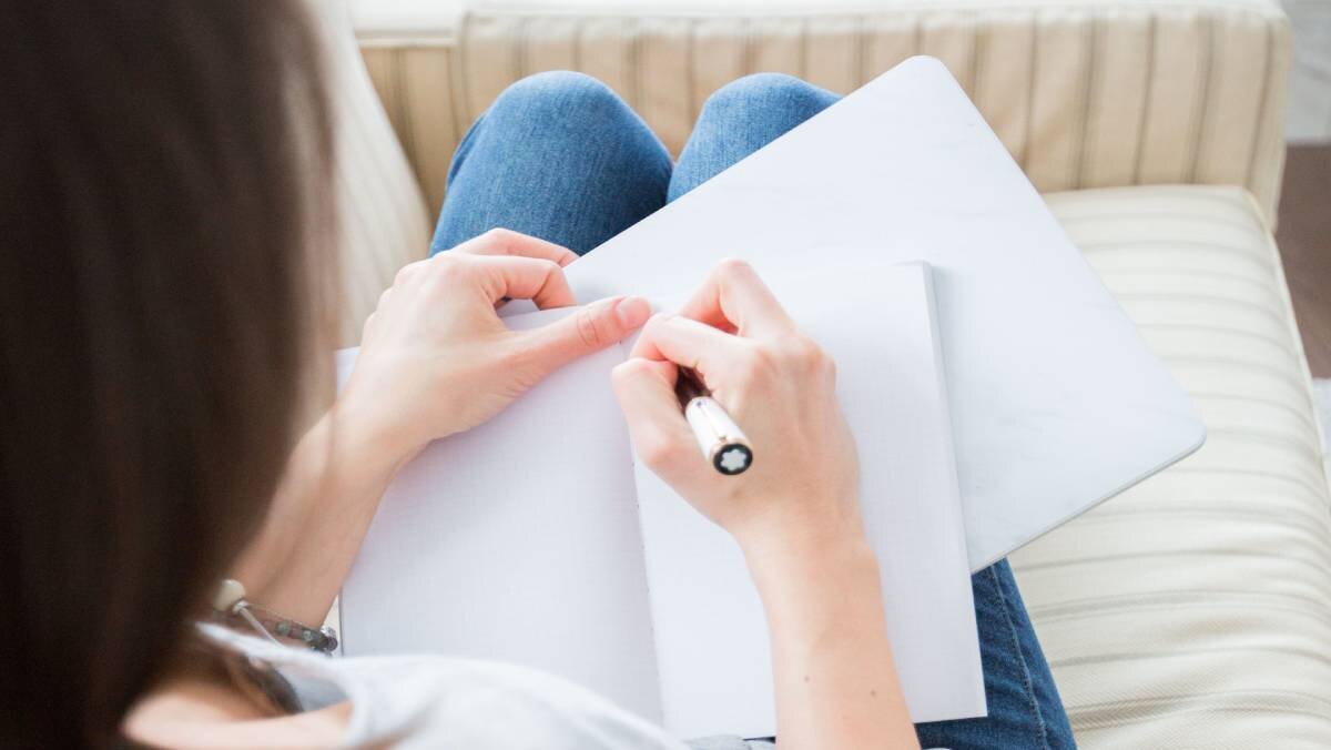 Woman about to write on a small notebook