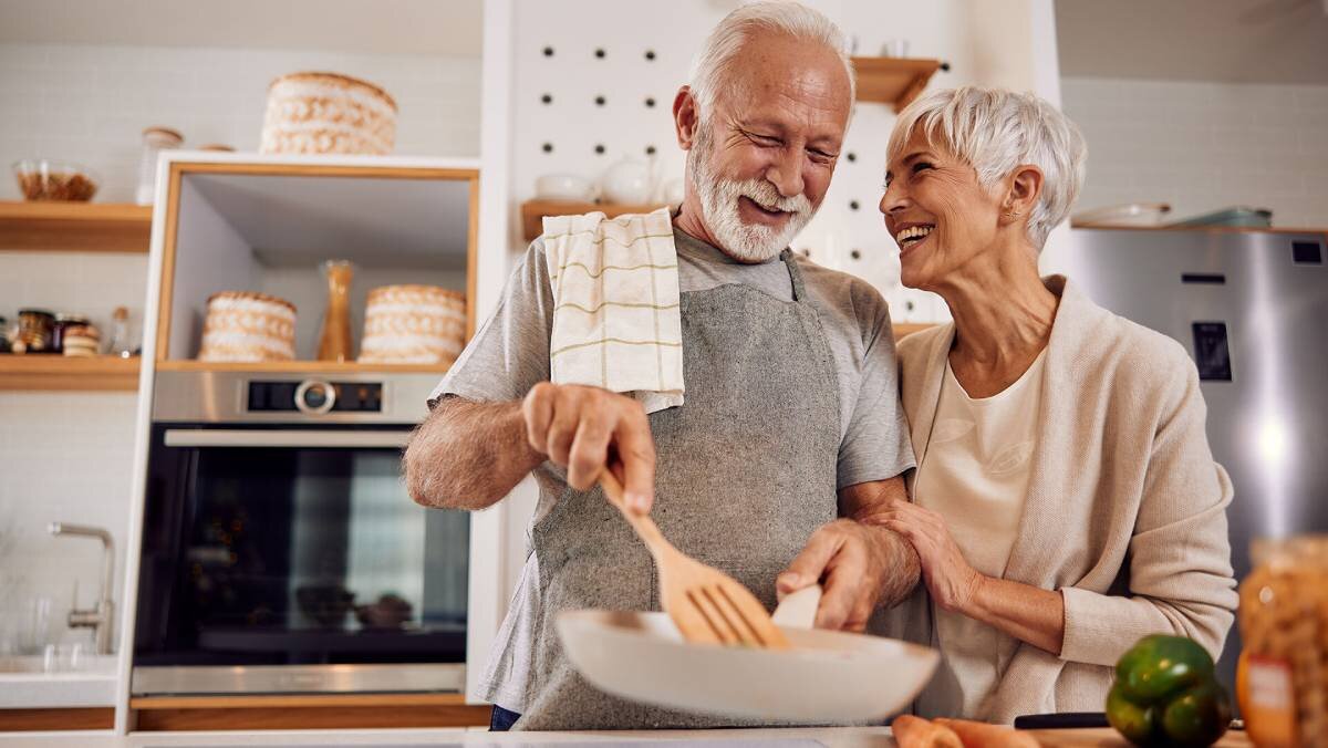 Senior couple cooking and smiling