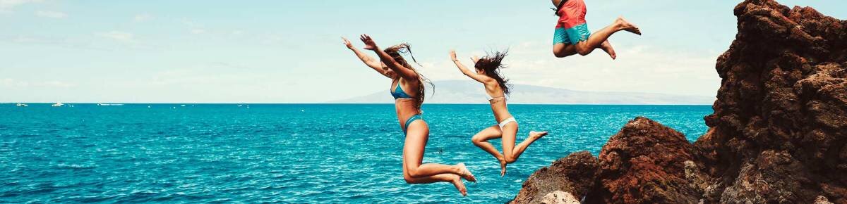 3 people jumping into the water from a cliff