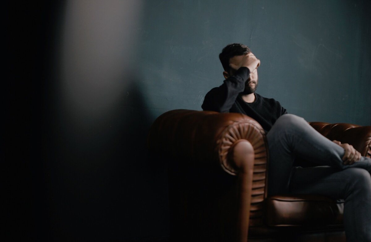 A man holding his forehead, appearing to have a headache or migraine