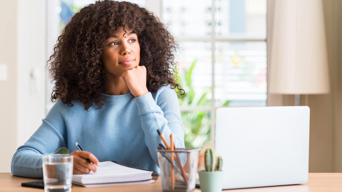 A woman sitting at a desk, holding a pen in her hand, deep in thought