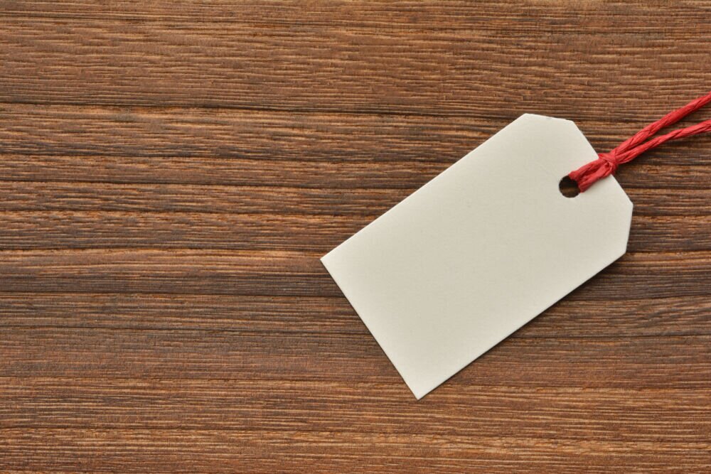 Blank white tag with a red string on a wooden surface