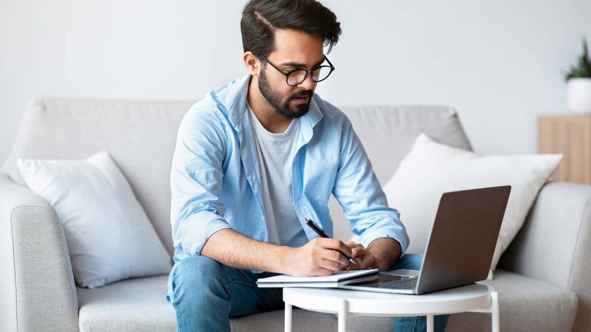 Man taking notes in front of his laptop