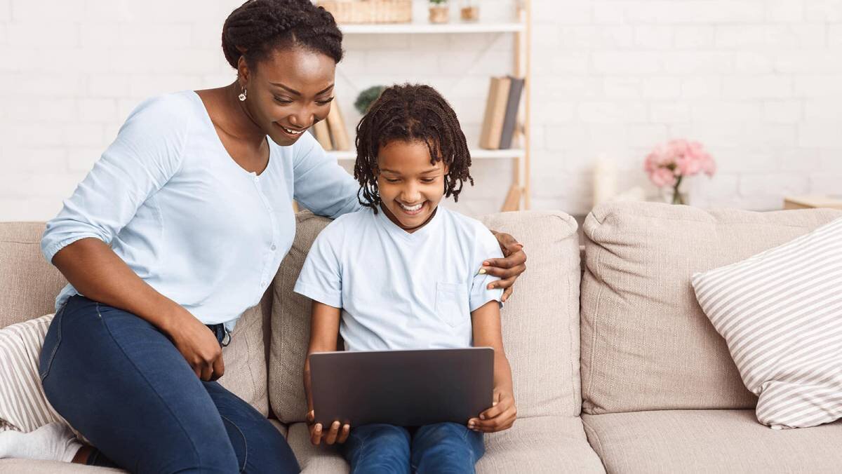 Mother and young daughter laughing in front of laptop