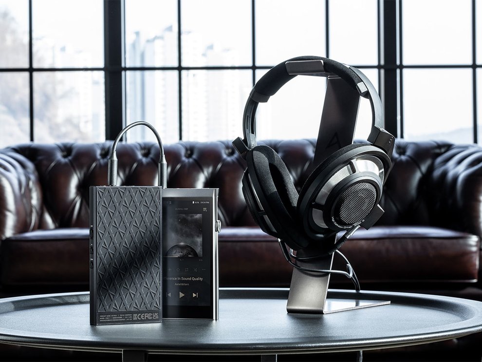 Astell&Kern PA10 Amp sitting on top of a coffee table with headphones and a music player in front of a leather couch.