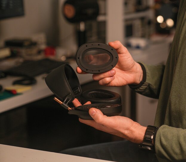 hands holding headphones with earpads and a screen in hand