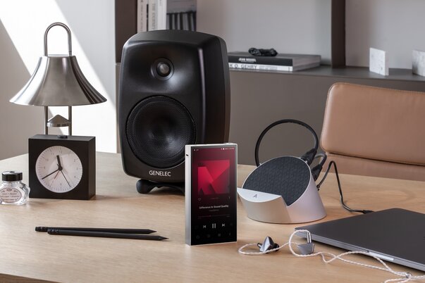 Astell&Kern PD10 & Cradle on table with alarm clock, IEMs, speaker, and laptop nearby