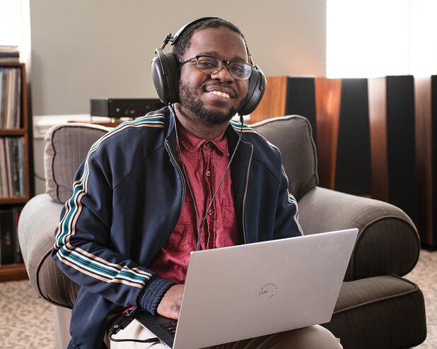 Devon James holding a laptop and wearing headphones