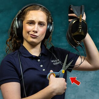 woman holding headphones with a scissor pointed at the headphone cable 