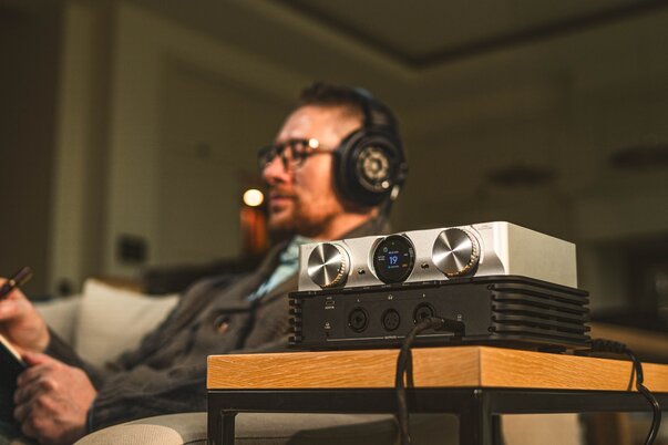 Man sitting with headphones on next to the iFi Audio iDSD Phantom DAC Headphone Amp
